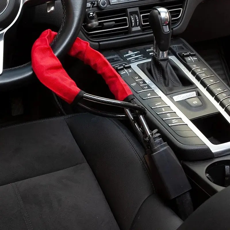 Steering wheel cable lock looped around wheel and clicked into seatbelt buckle as a visible theft deterrent.
