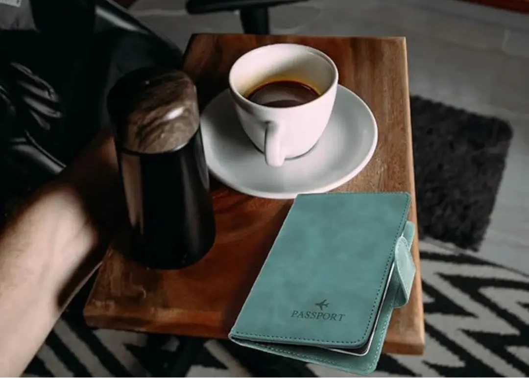 Tea cup and saucer on a wooden tray with a signal blocking passport holder, in a cozy room setting.