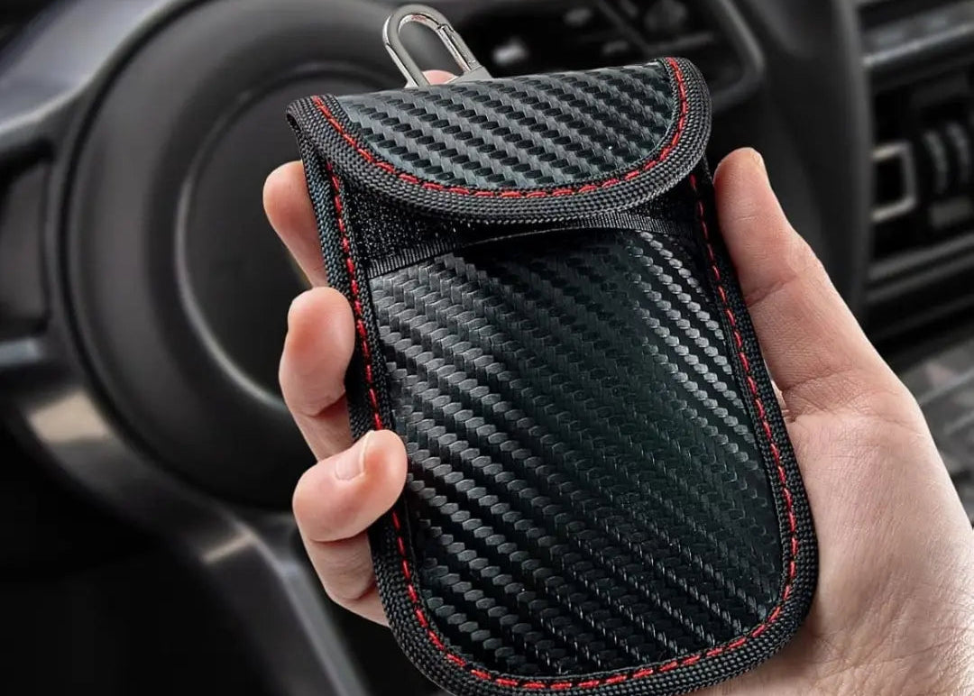 Carbon fiber patterned faraday pouch held in a hand with car interior background
