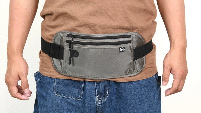 Person wearing a gray waist bag with a black strap on a plain background
